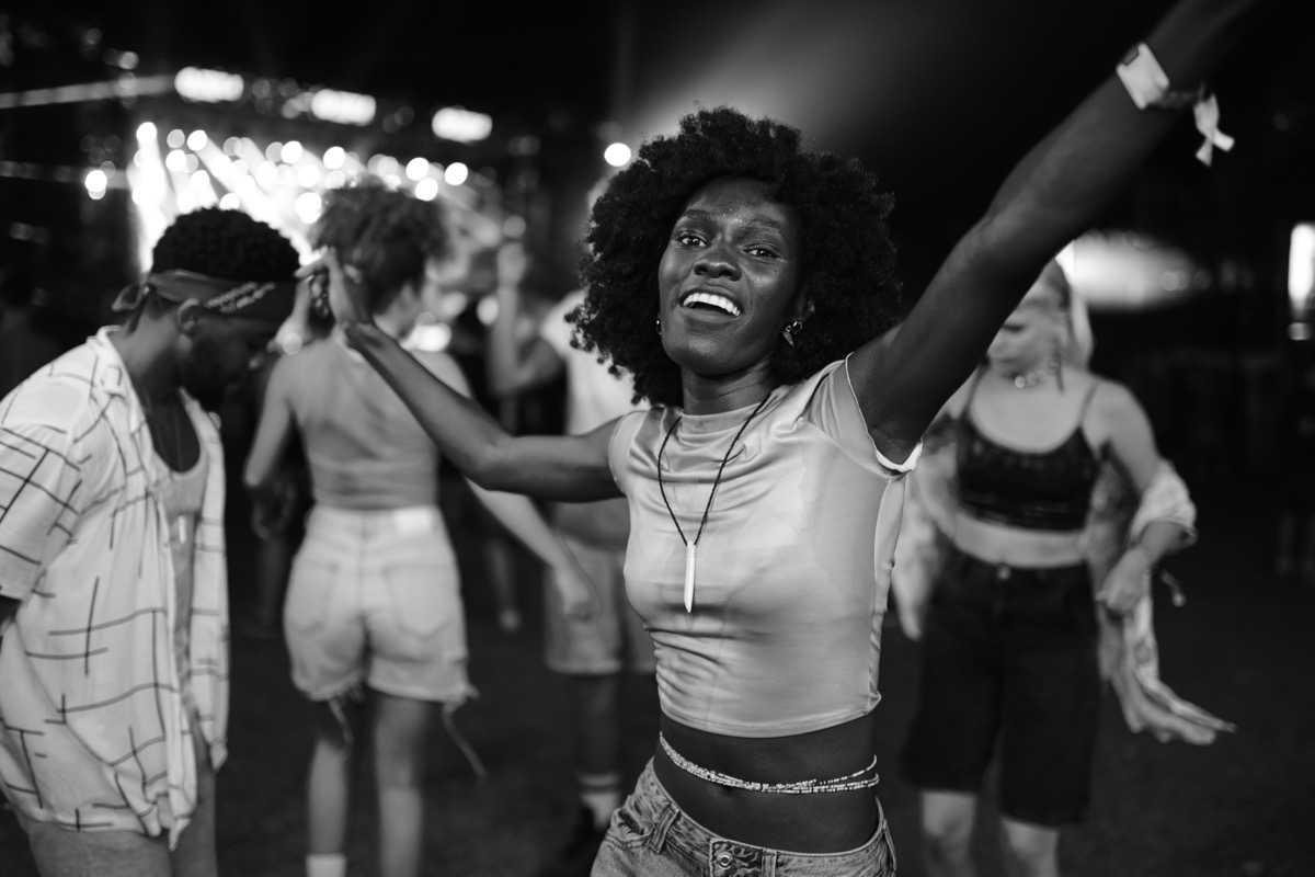A woman dancing with her arms out at a nighttime music festival.
